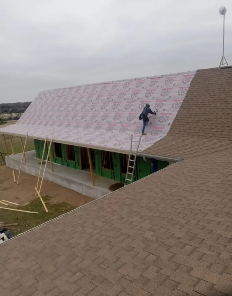 Worker preparing underlayment for a metal roof installation in Holdenville